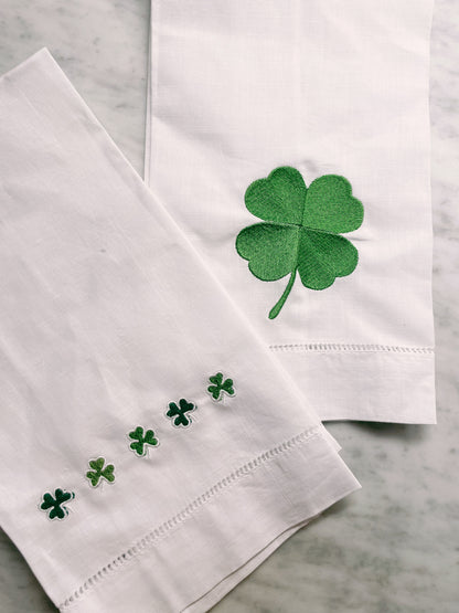 White napkins with green four-leaf clover designs on a marble surface