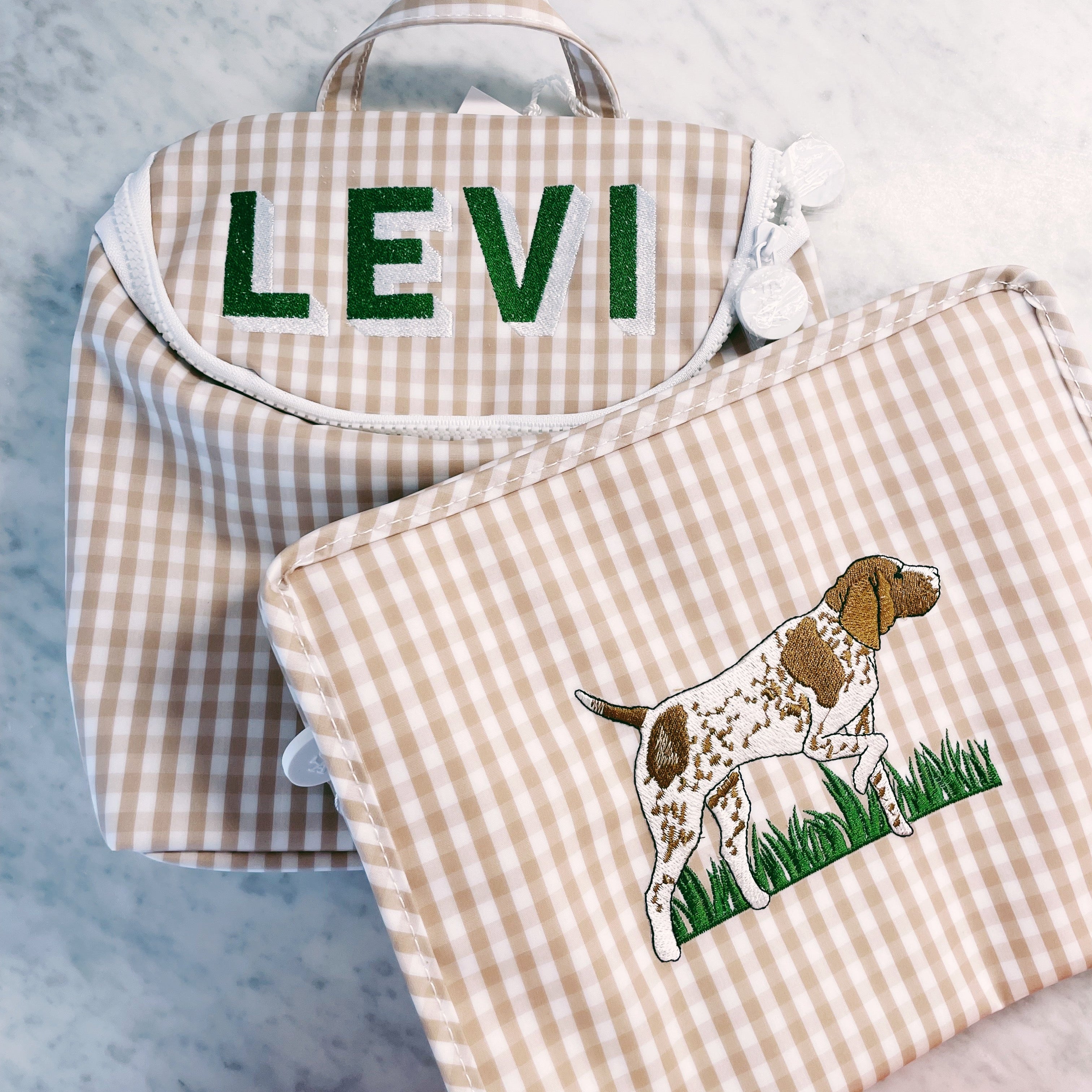 Checkered bags with 'LEVI' embroidered on one and a dog illustration on the other, against a light blue background.