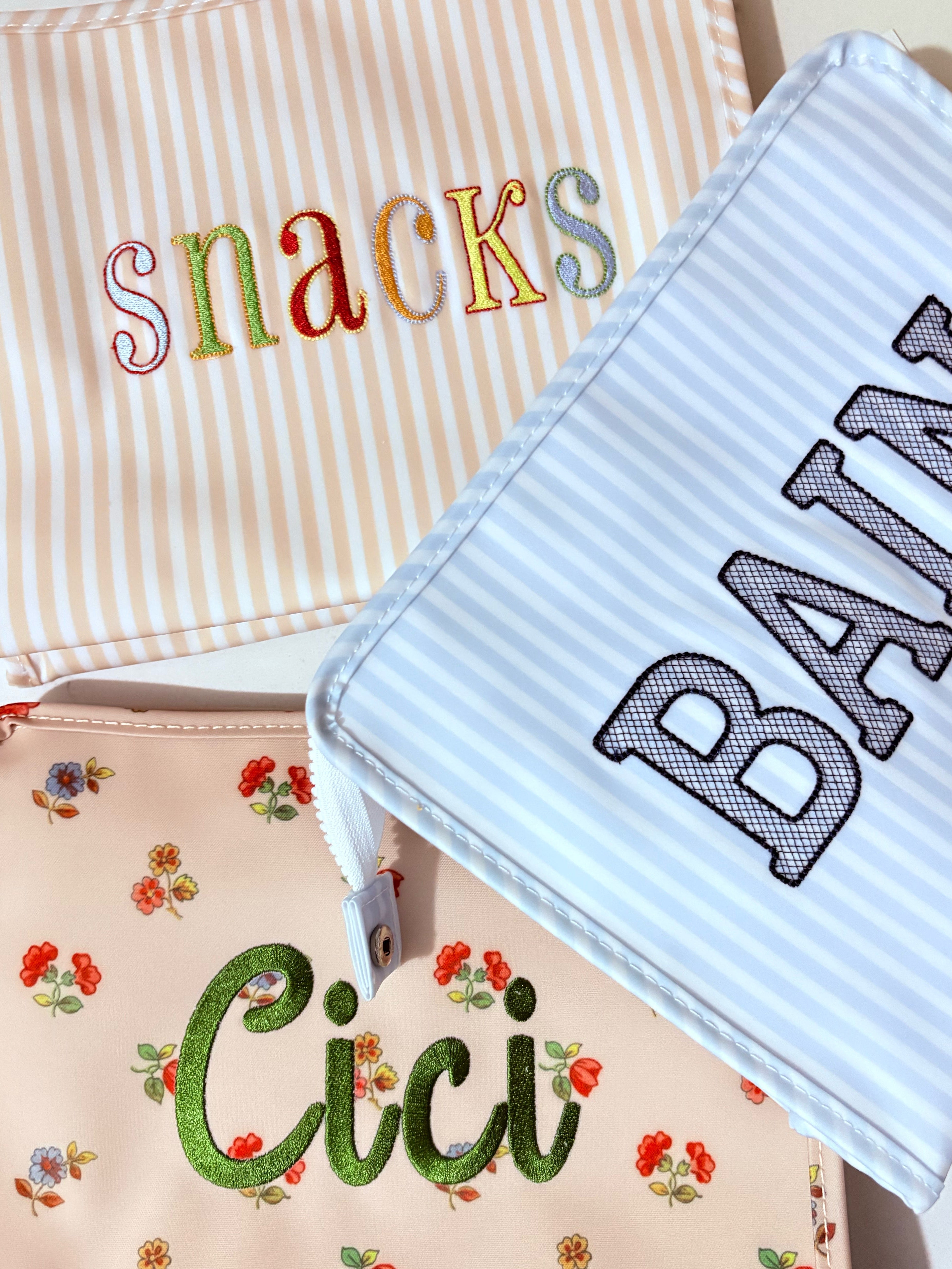 Three fabric bags with embroidered text on a neutral background