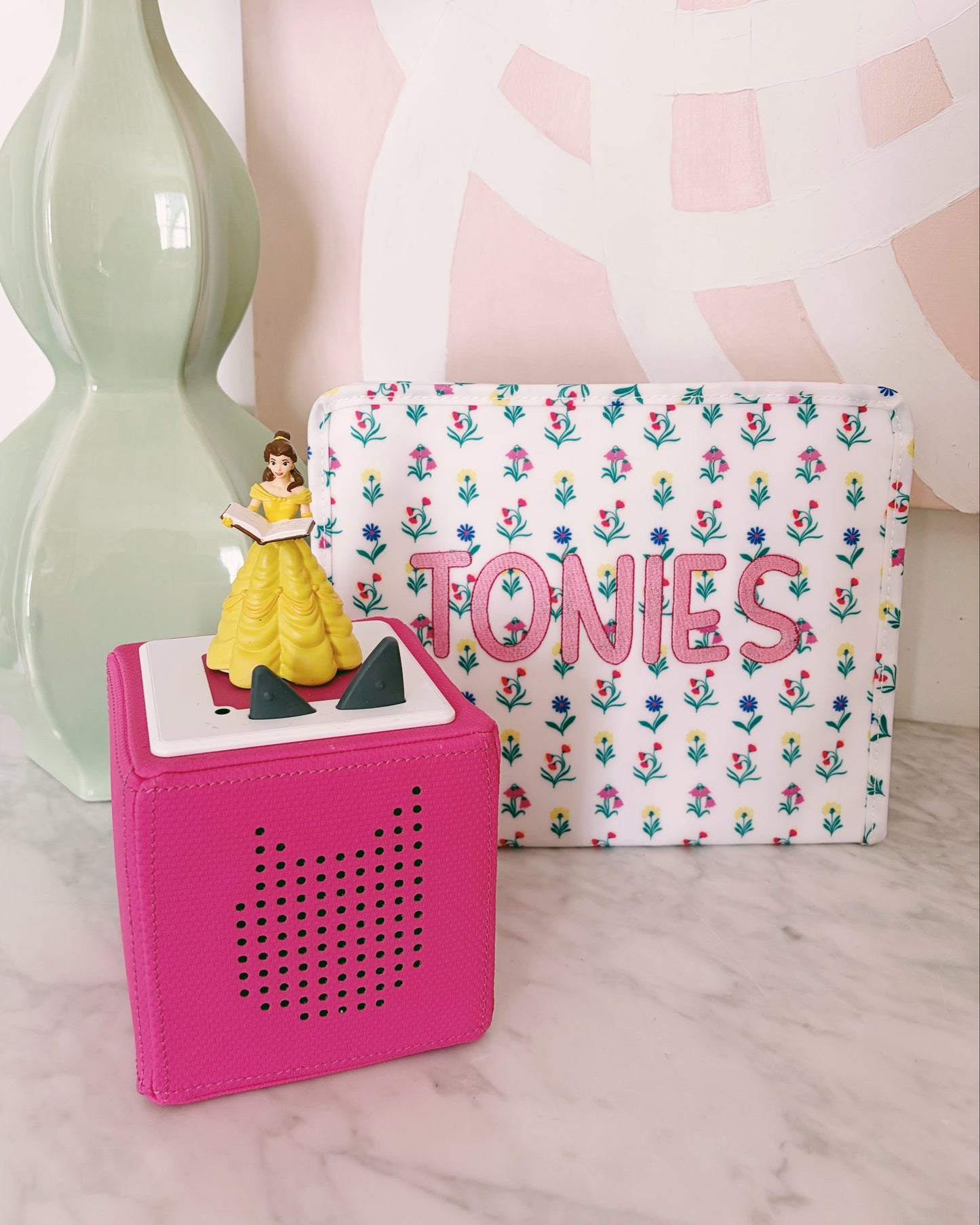 Small figurine of a princess on a pink block with a floral-patterned pouch labeled 'TONIES' in the background.